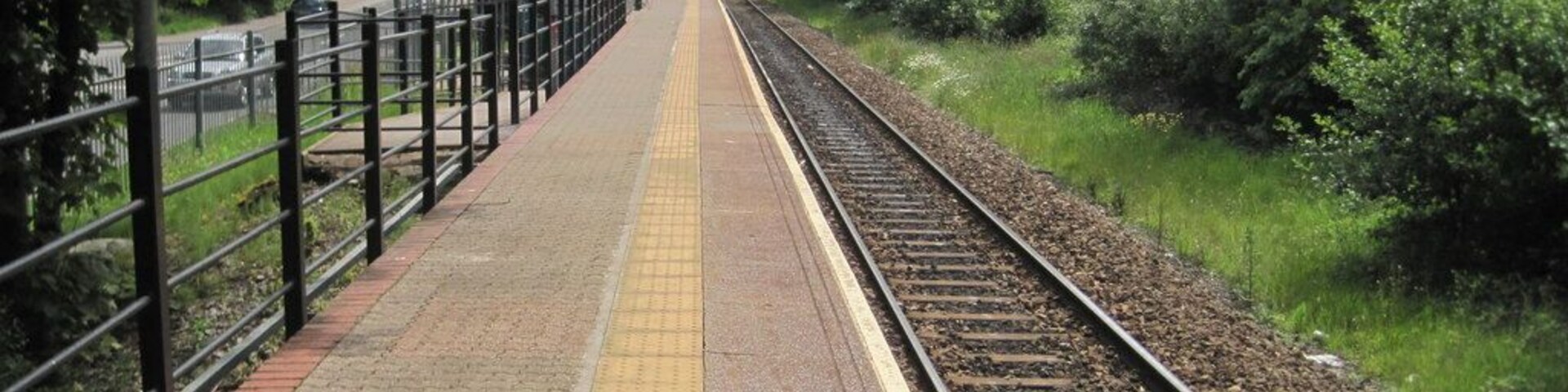 Un andén de tren con un cartel que dice 'Ynyswen' y una valla a un lado.