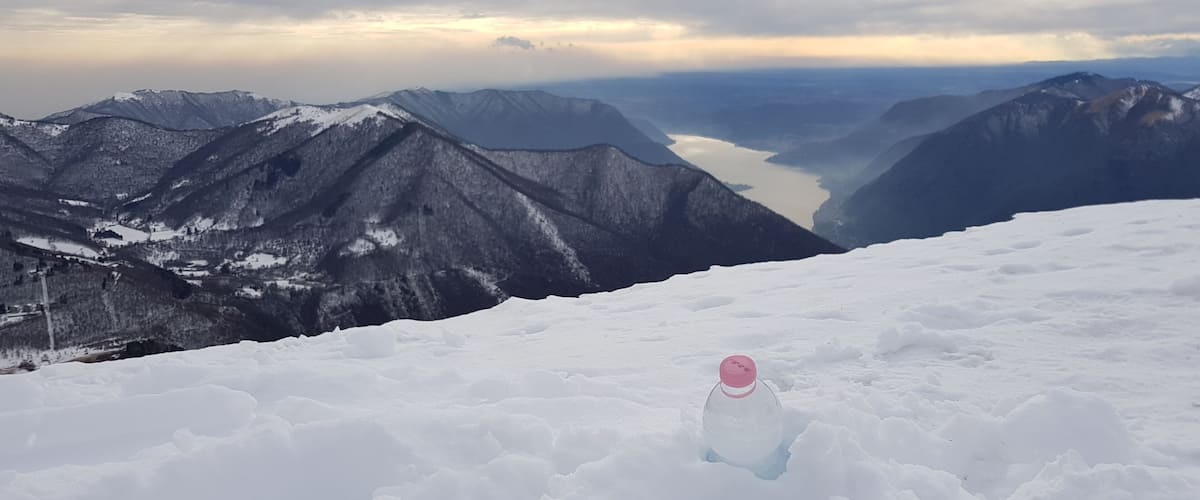 A snowy mountain landscape with a clear sky and a bottle in the foreground.