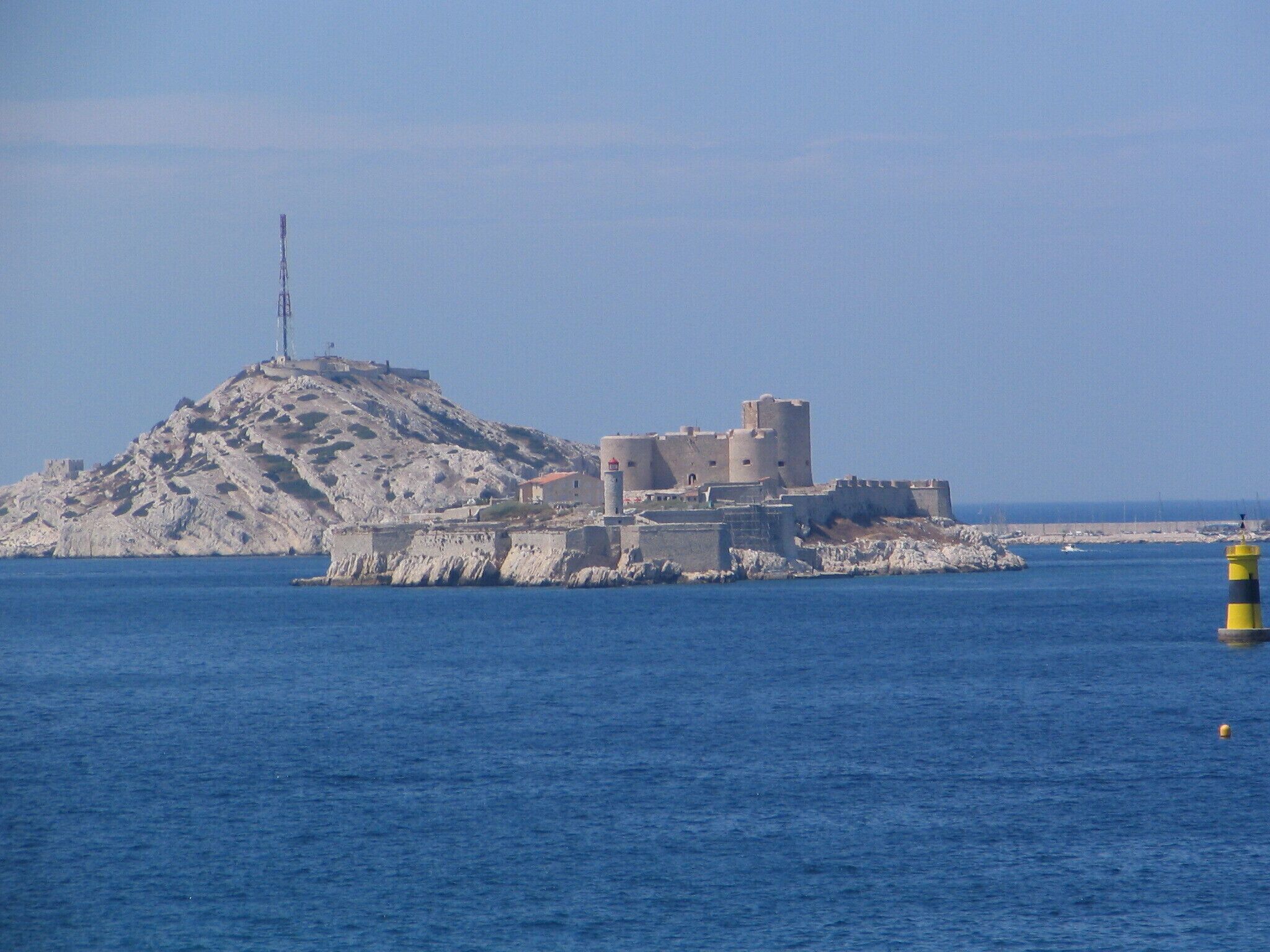 A coastal fortress on a rocky island with a lighthouse in the foreground.