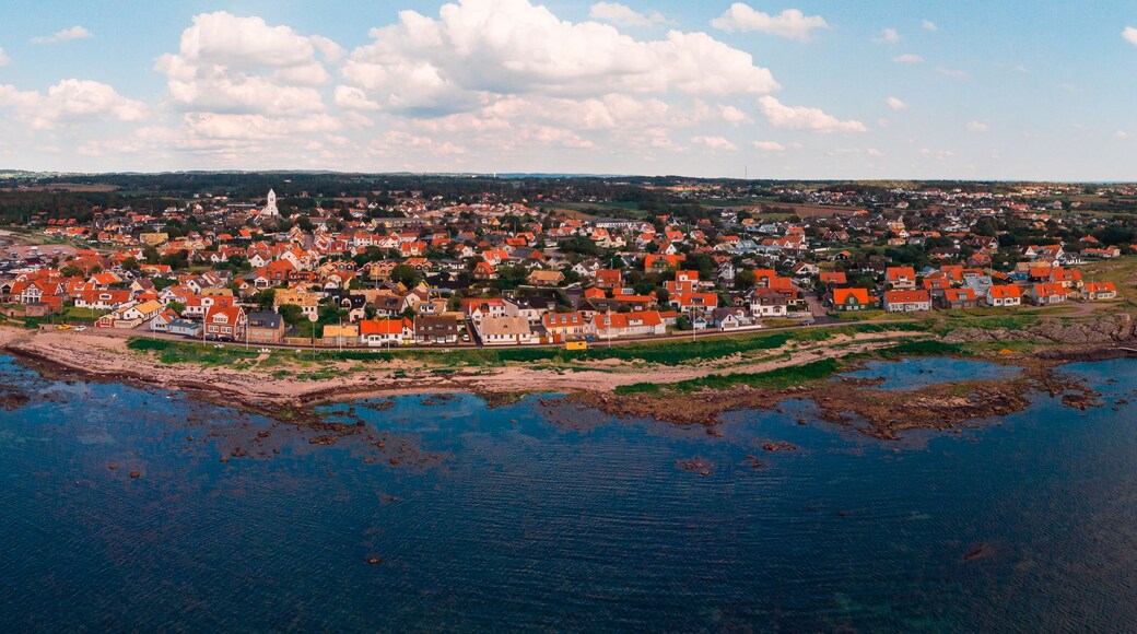 A coastal town with a dense cluster of red-roofed houses, a prominent church, and a pier extending into the water.