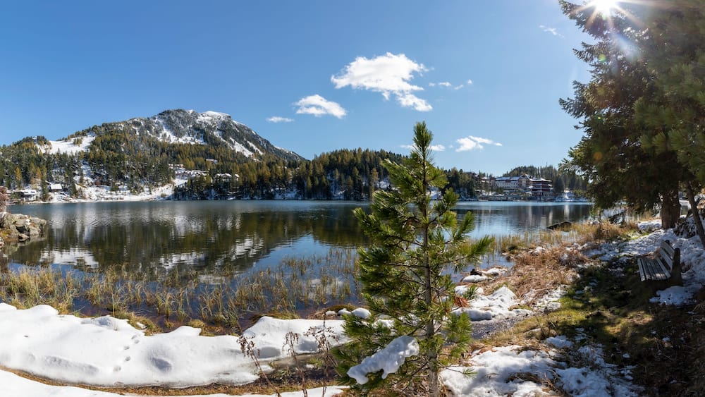 Un lac recouvert de neige, avec des montagnes en arriÚre-plan et un ciel dégagé.