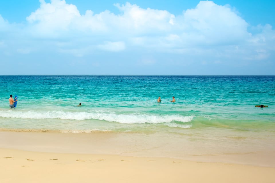 A beach with clear turquoise water and a sandy shore.