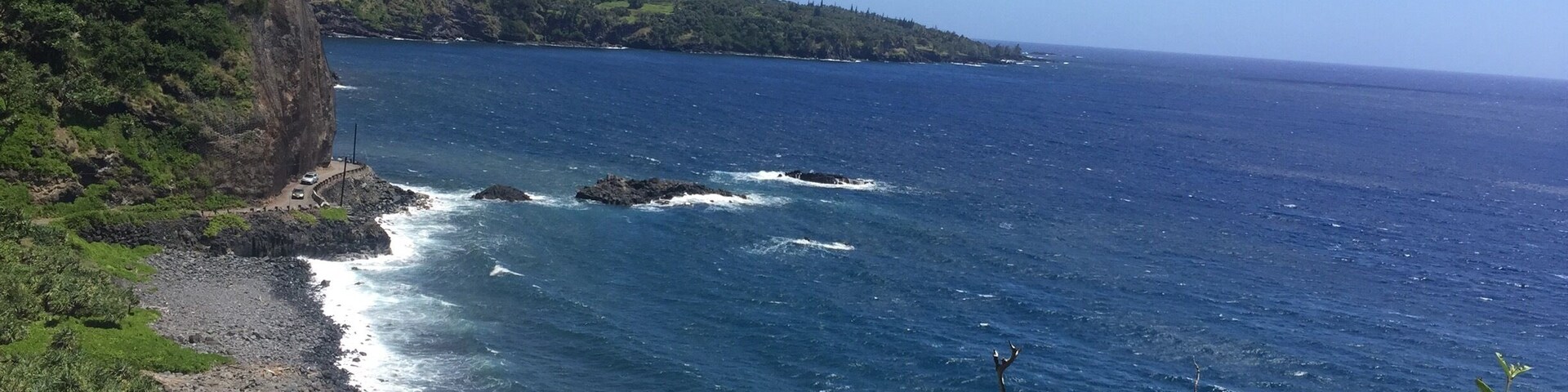 Un paisaje costero con un litoral rocoso, un mar azul cristalino y abundante vegetación.