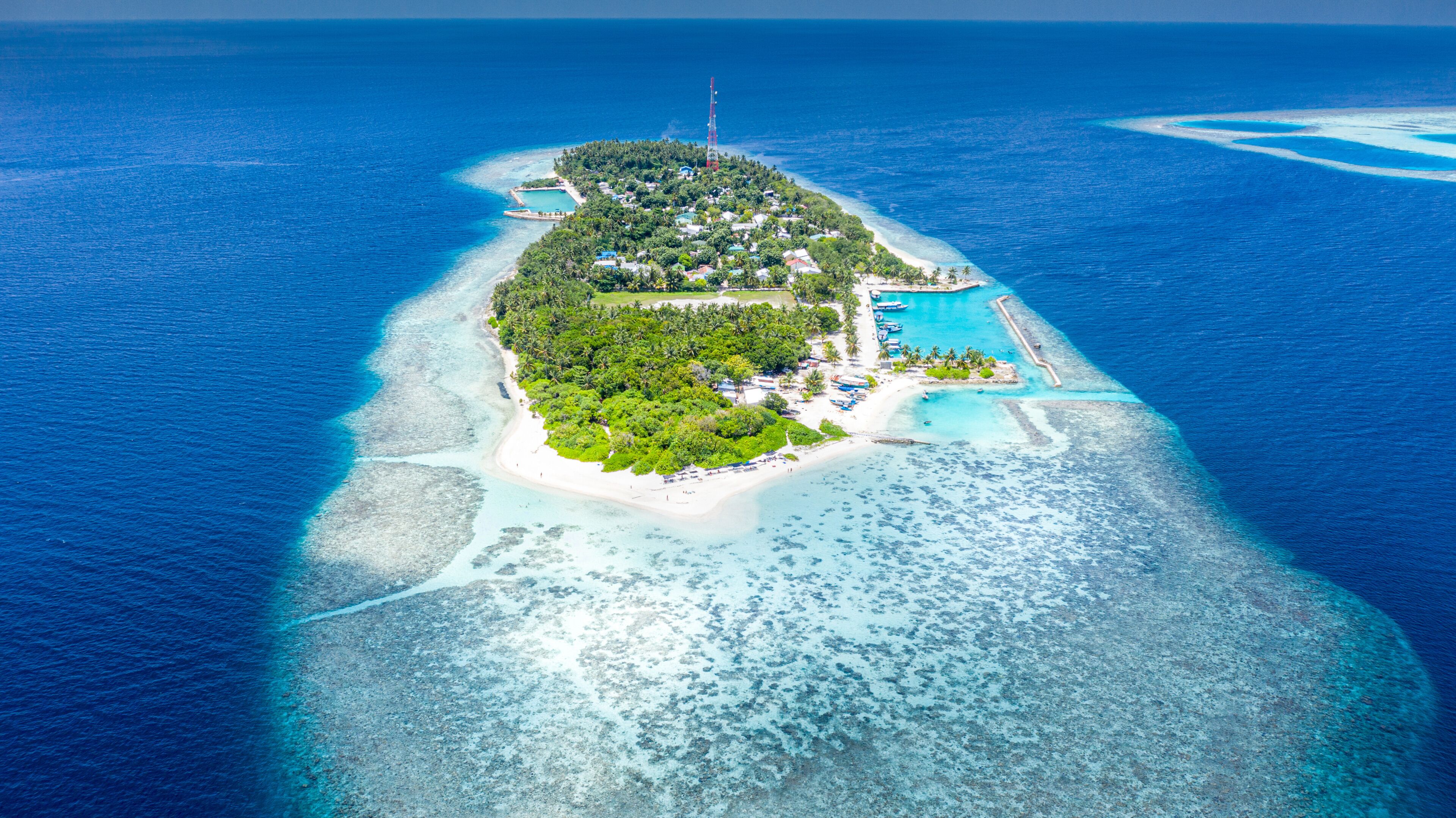 Une île avec une mer d’un bleu limpide, une plage de sable blanc et une petite piscine.