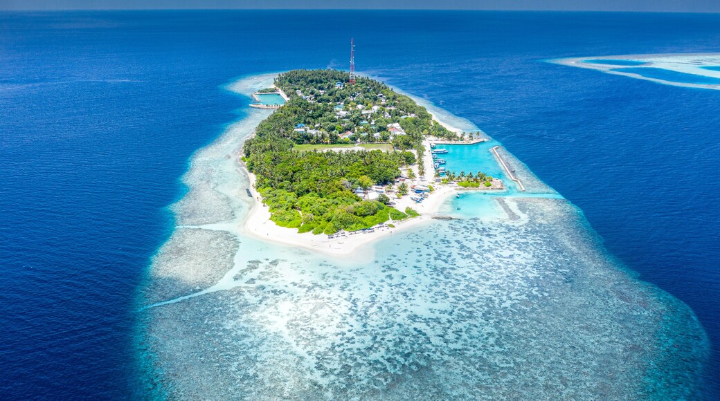 Une Ăźle avec une mer dâun bleu limpide, une plage de sable blanc et une petite piscine.