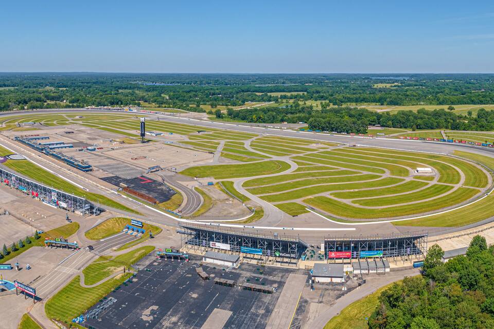 Luchtbeeld van een racecircuit met meerdere rijbanen, tribunes en een groot parkeerterrein.