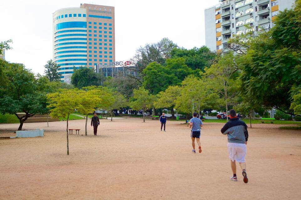 A park with trees, a dirt path, and buildings in the background.
