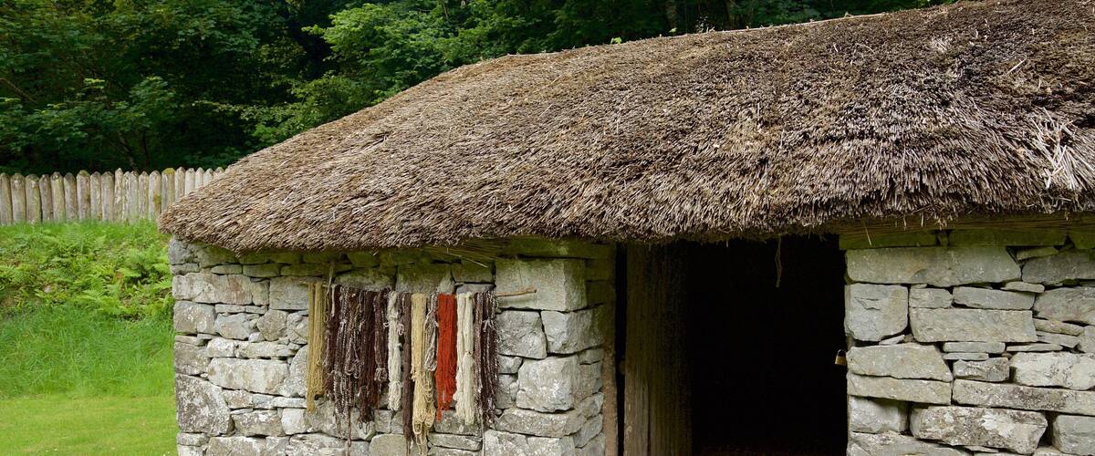 A stone cottage with a thatched roof and a wooden door.