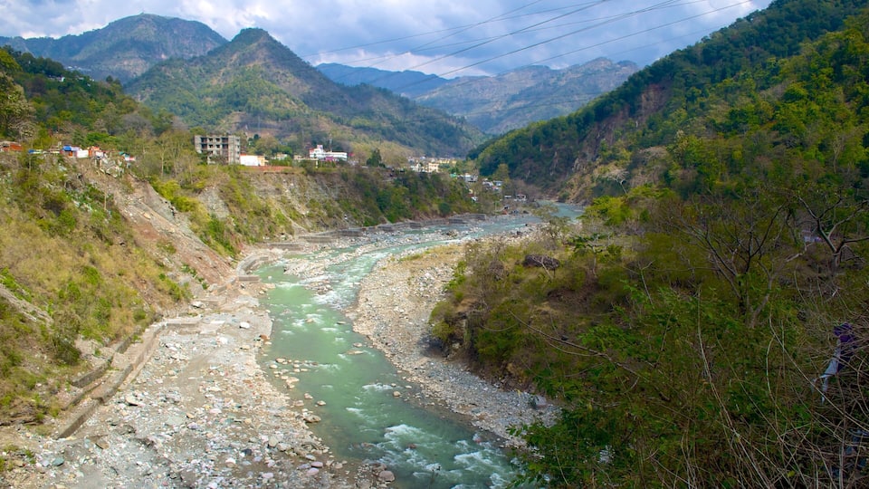 A river flowing through a mountainous valley with buildings on the left bank.