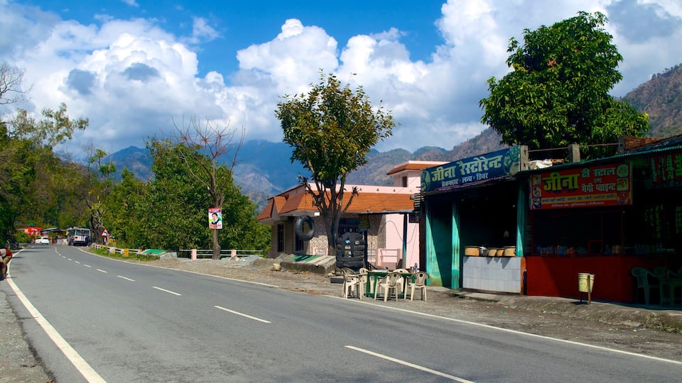 A road with a shop on the right and mountains in the background.