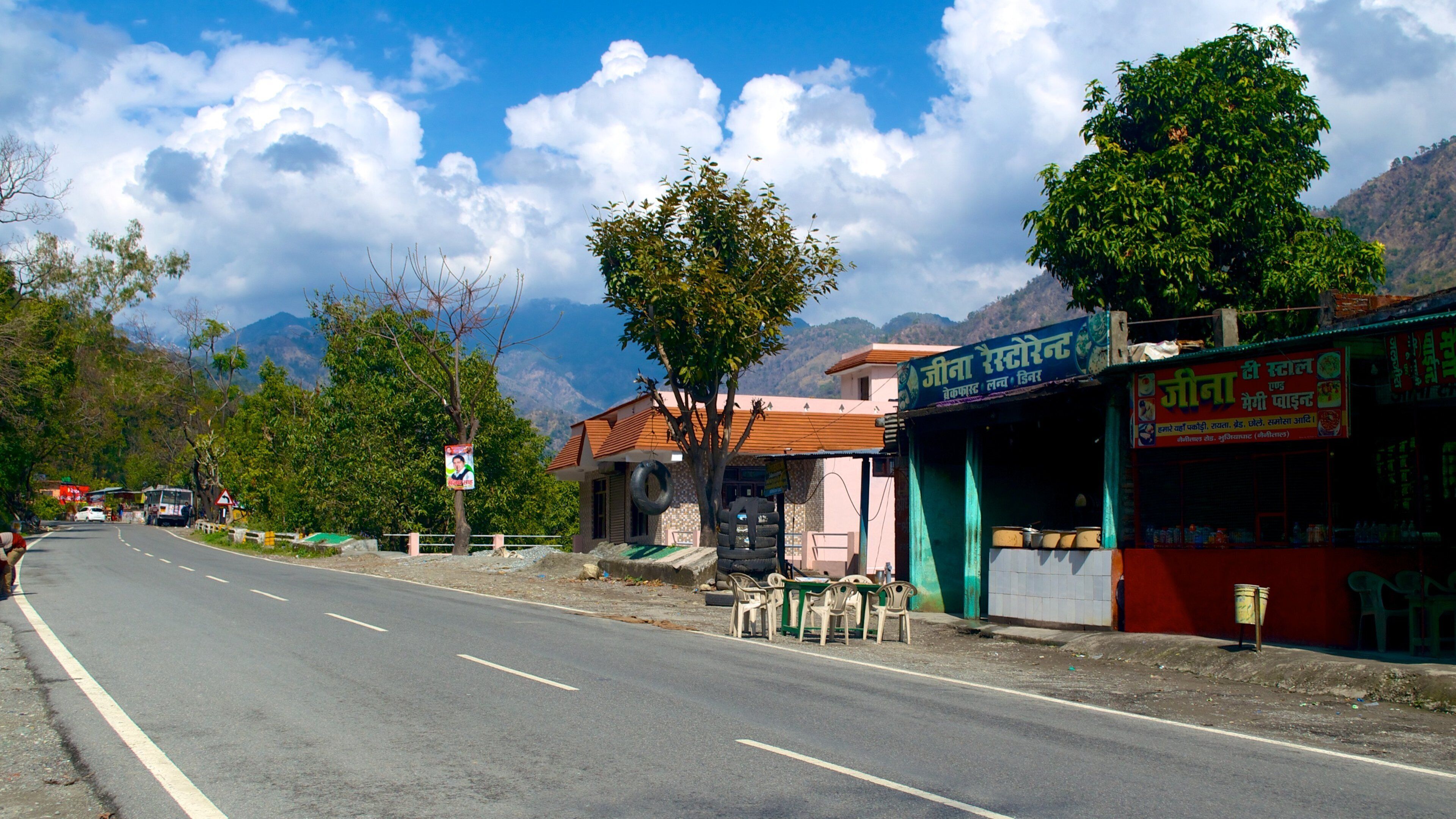 A road with a shop on the right and mountains in the background.
