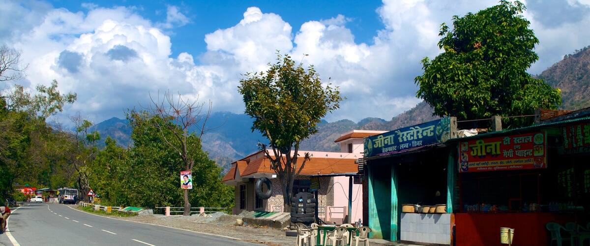 A road with a shop on the right and mountains in the background.
