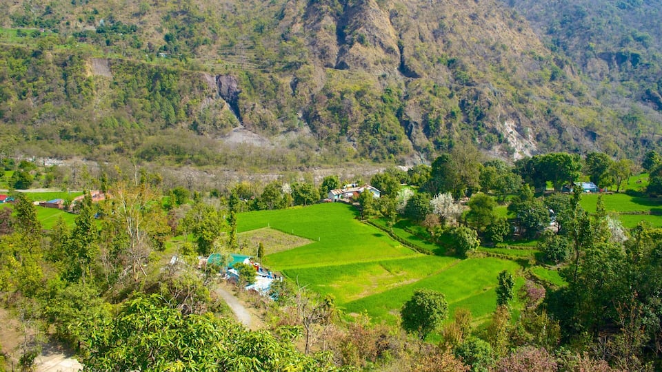 A rural landscape with terraced fields, scattered houses, and a mountainous backdrop.