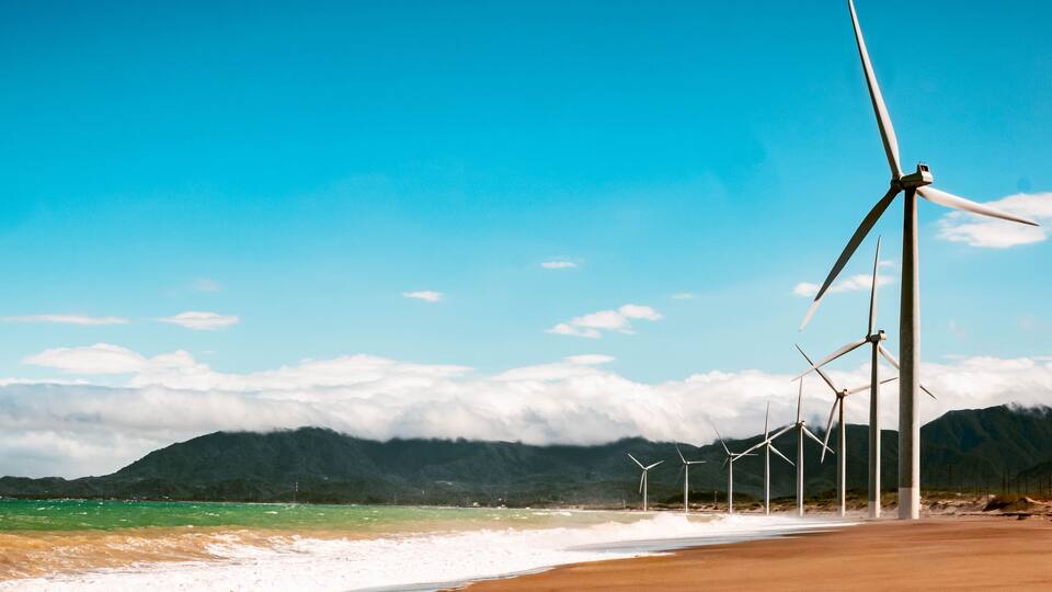 Aerial view of Bangui Wind Farm windmills along the coast of Ilocos Norte, Philippines at sunset.