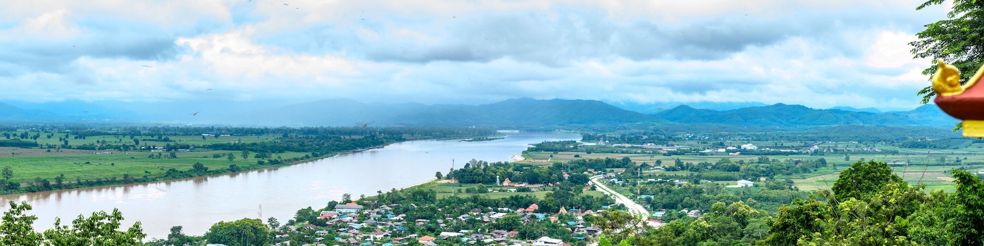 Um rio serpenteando por uma cidade rodeada por montanhas e vegetação.