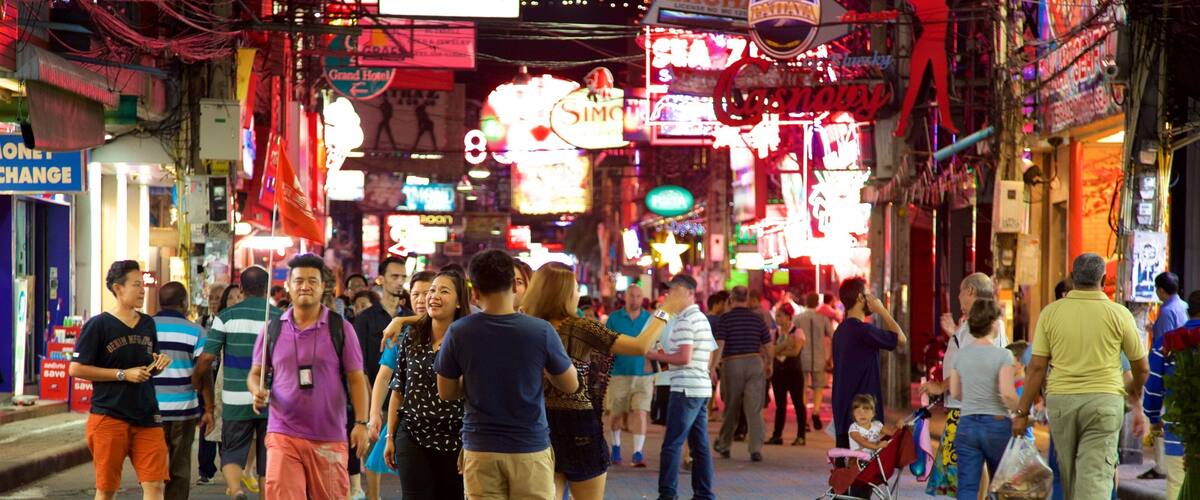 A busy street at night with neon signs and people walking.