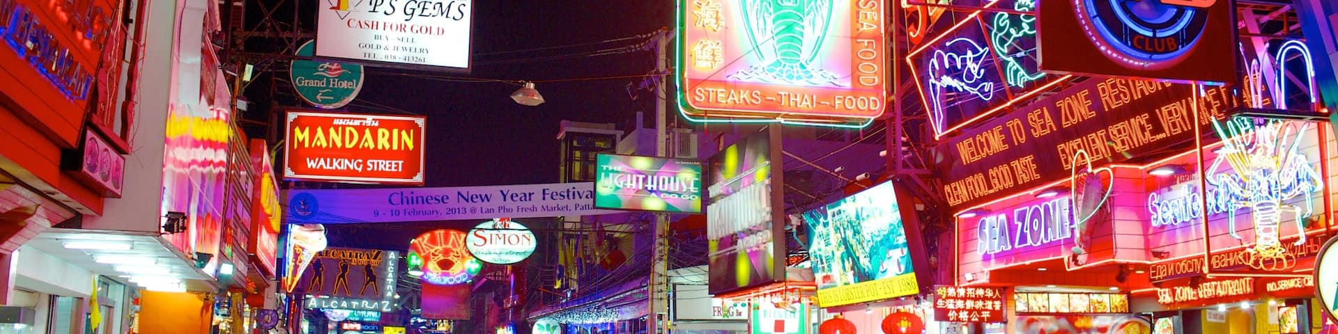 A neon-lit street with signs for restaurants and shops, including 'Sea Zone' and 'Lobster Pot'.