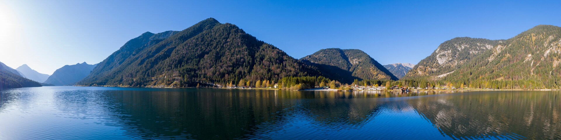 Un lago tranquilo rodeado de montañas con un cielo despejado.