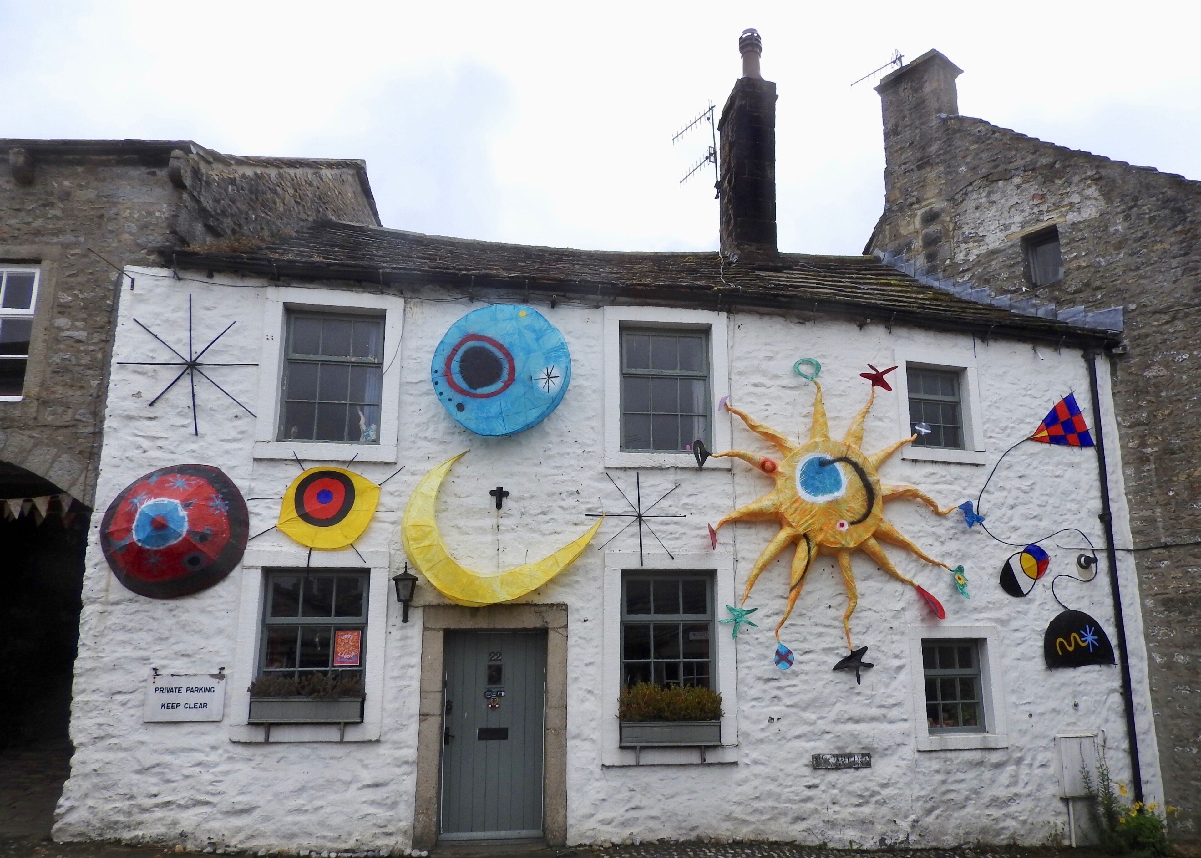 A white building with colorful decorations including a sun, moon, and various shapes.