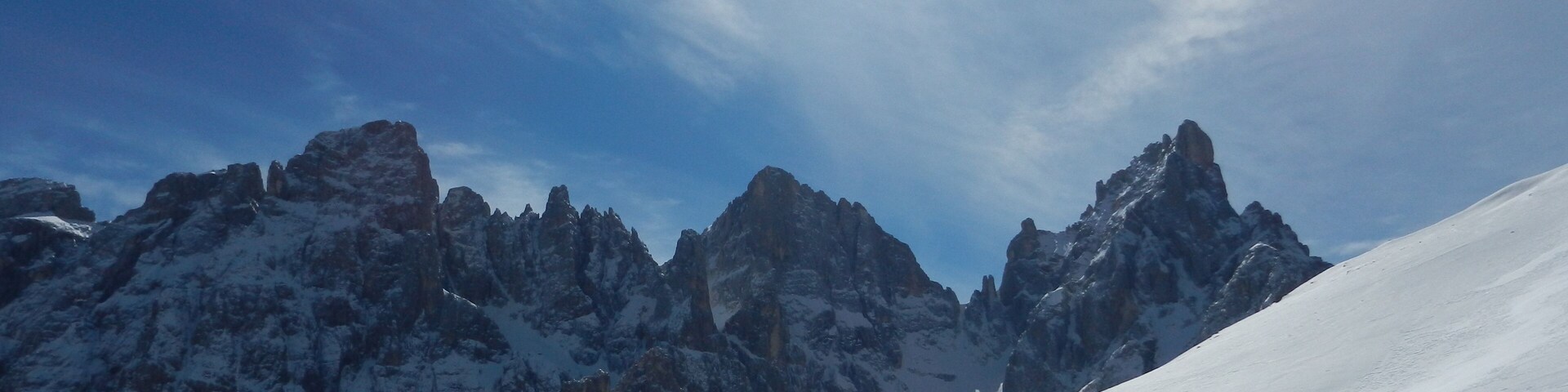 Cordilheira nevada com picos pontudos sob um céu limpo.