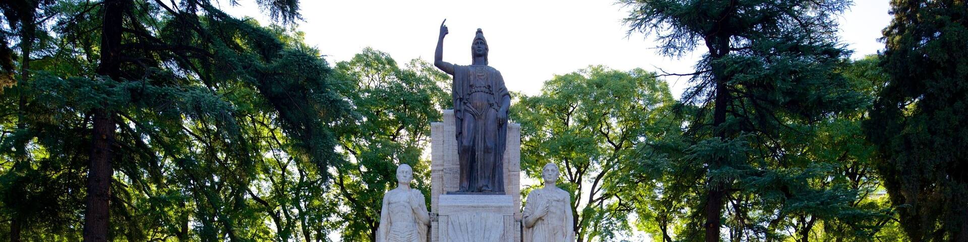 A statue of a historical figure surrounded by trees in a park.