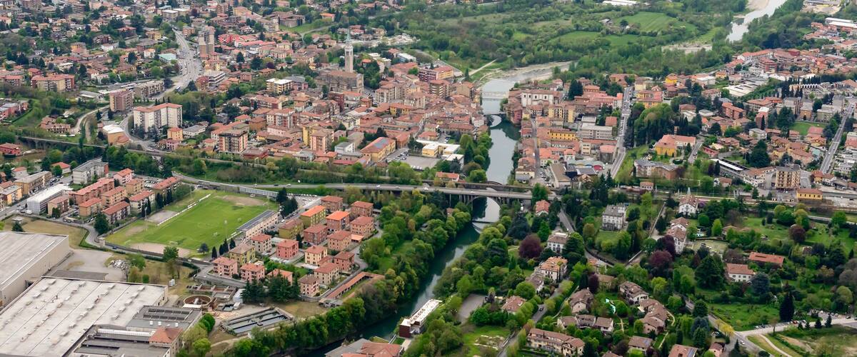 A densely built urban area with a river running through it, surrounded by green spaces and fields.