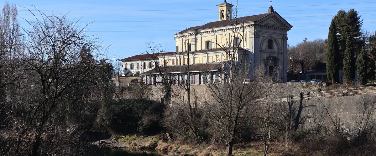 A historic building with a large tower and a river in the foreground.
