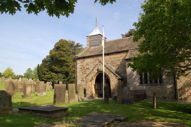 A stone church with a bell tower, surrounded by a cemetery with headstones.
