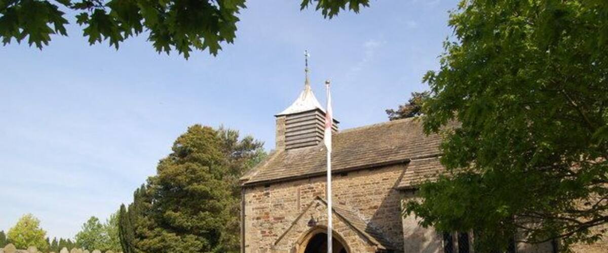 A stone church with a bell tower, surrounded by a cemetery with headstones.