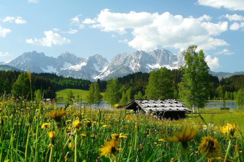 A mountain landscape with a cabin and a lake.