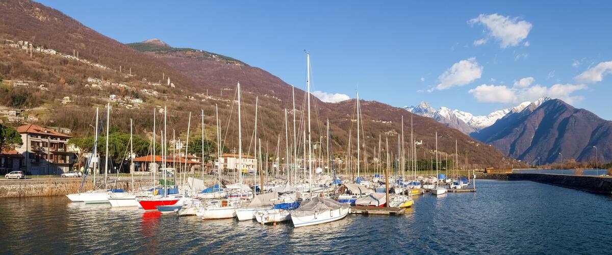 A marina with boats docked, surrounded by mountains and a clear sky.