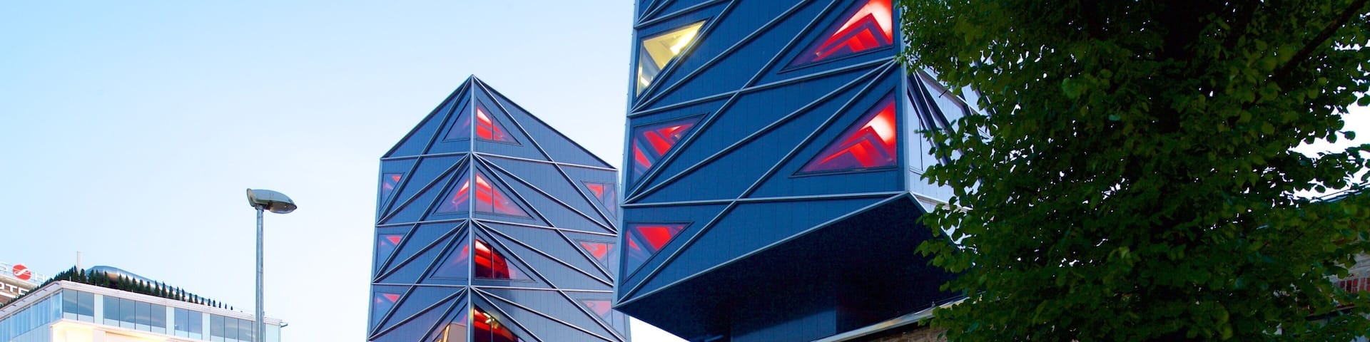 A modern building with geometric patterns and a brick structure with a cafe in front.