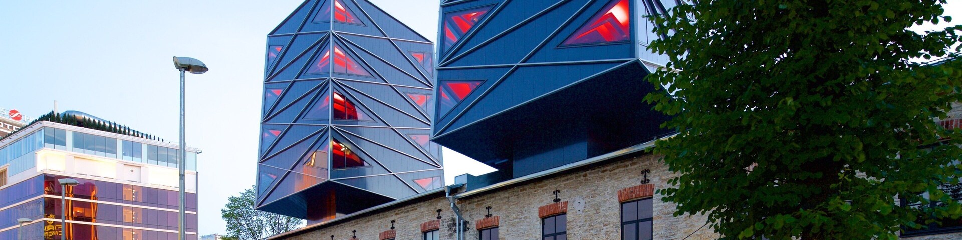 Um edifício moderno com padrões geométricos e estrutura de tijolos, com um café na frente.