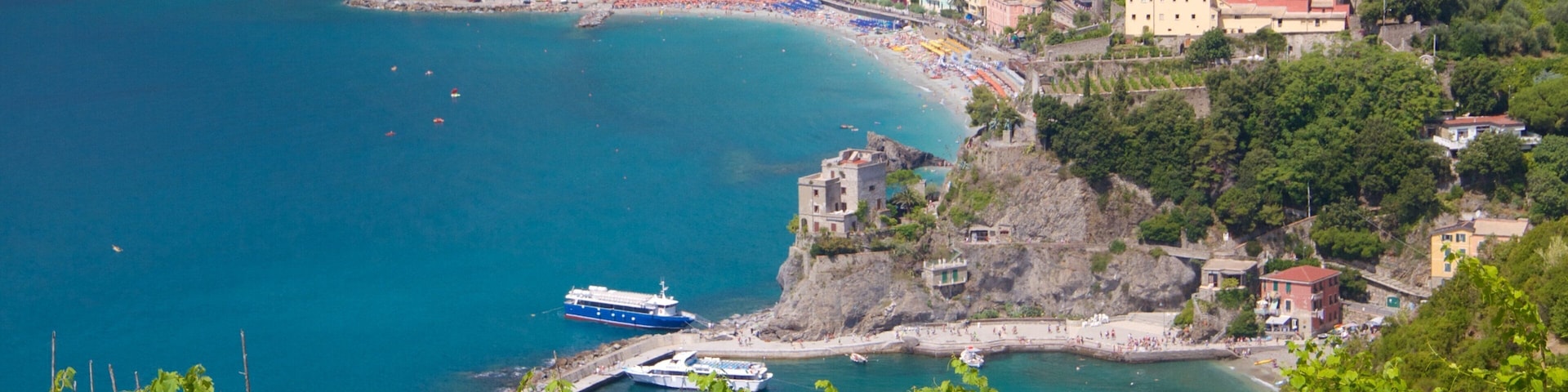 A coastal town with a beach, boats, and a castle-like structure on a cliff.