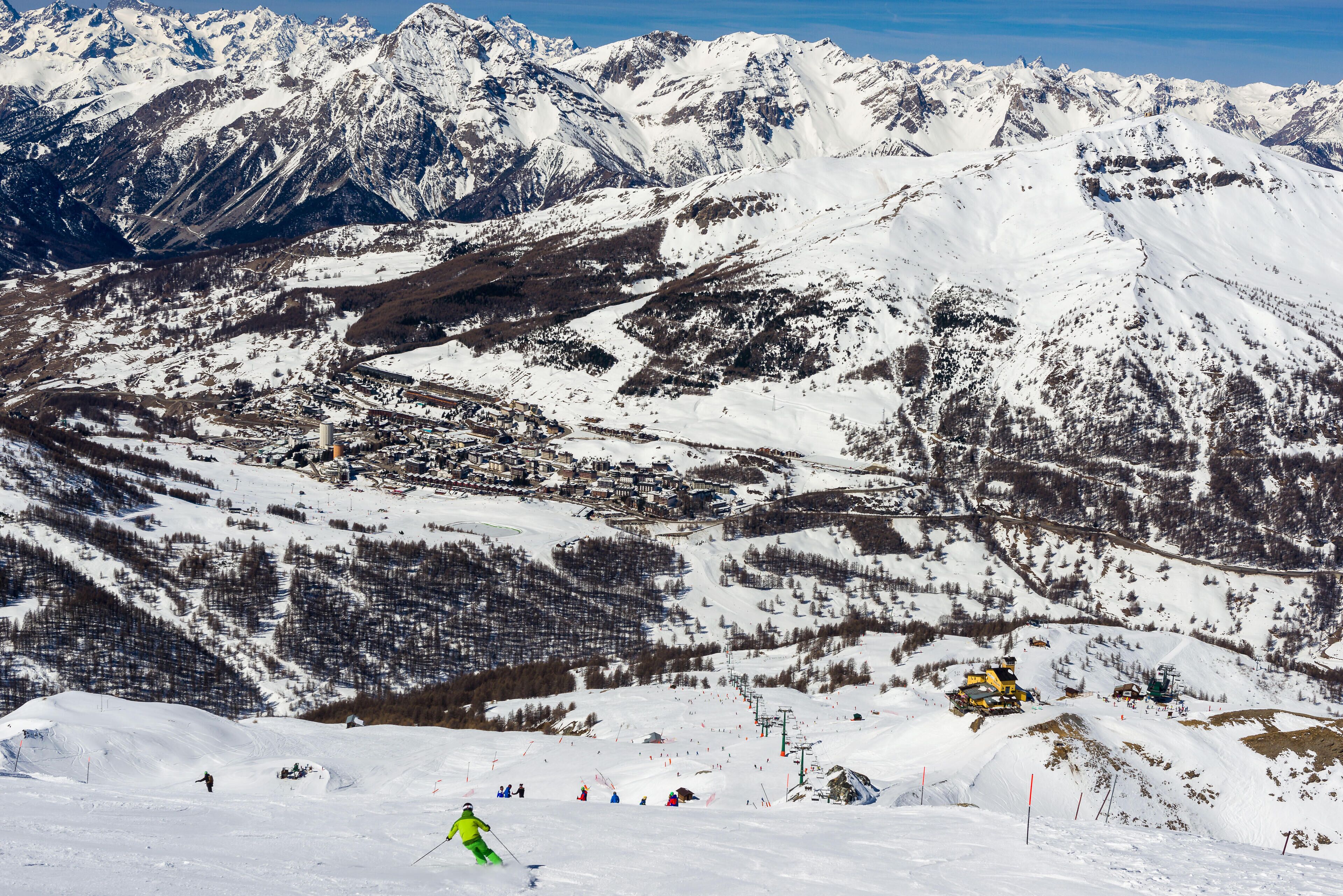 A snow-covered mountain landscape with ski slopes, a town, and a ski lift.