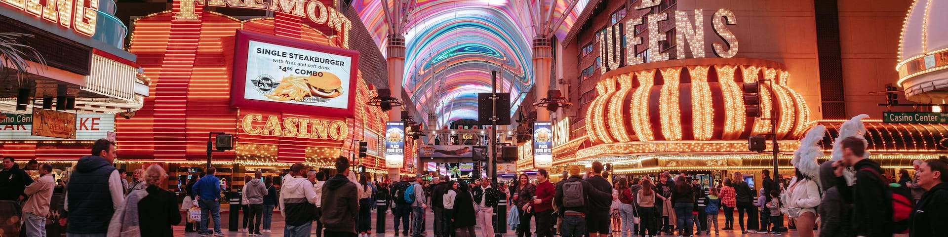 A brightly lit casino with neon signs and a colorful ceiling display.