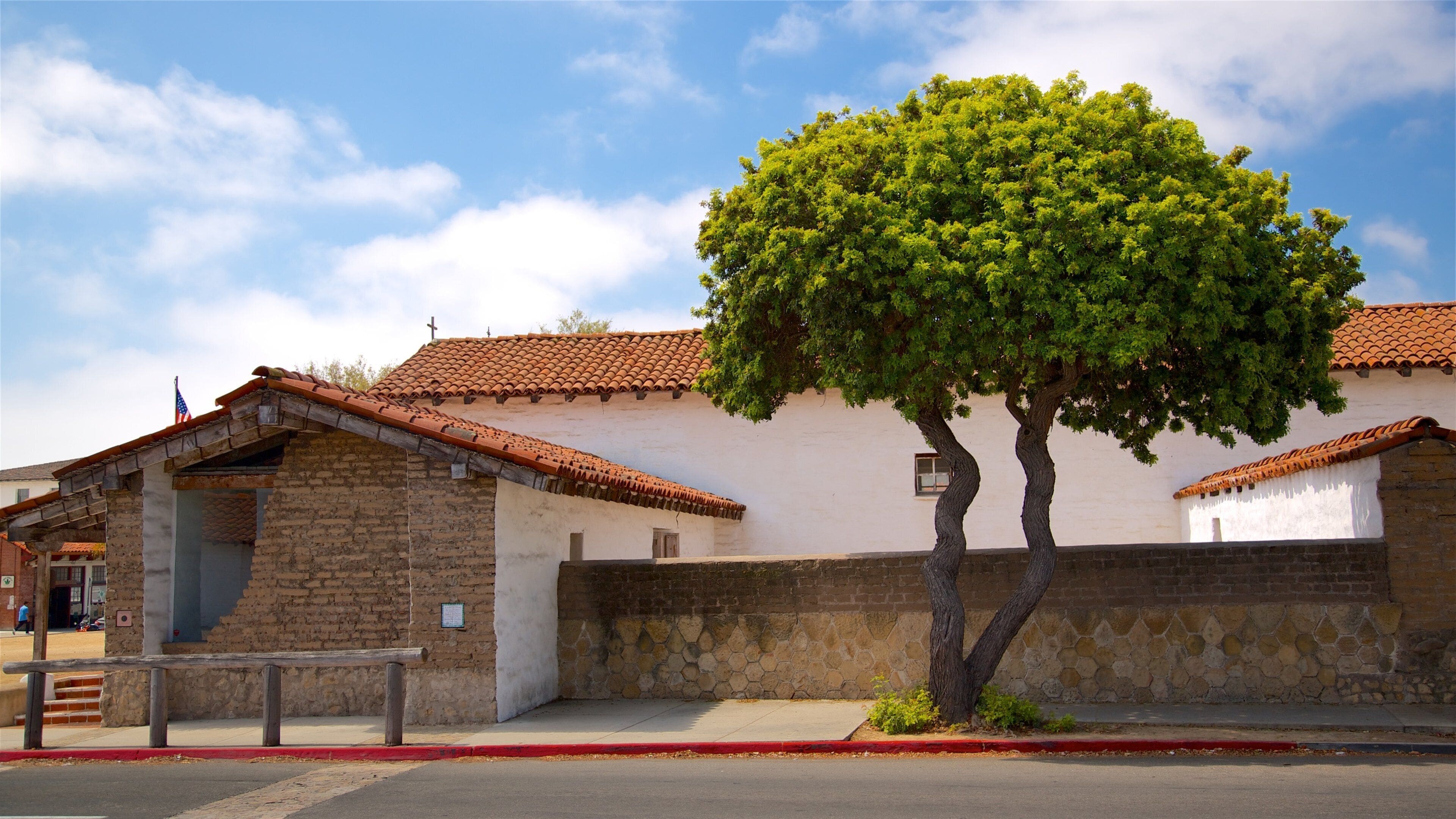 Un edificio tradicional con techo de tejas, pared de piedra y un árbol al frente.