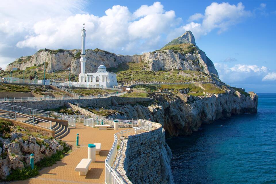 A coastal lighthouse, rocky cliffs, and a clear blue sea.