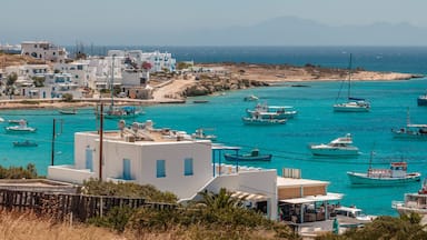 A coastal town with white buildings, turquoise waters, and several boats anchored near the shore.