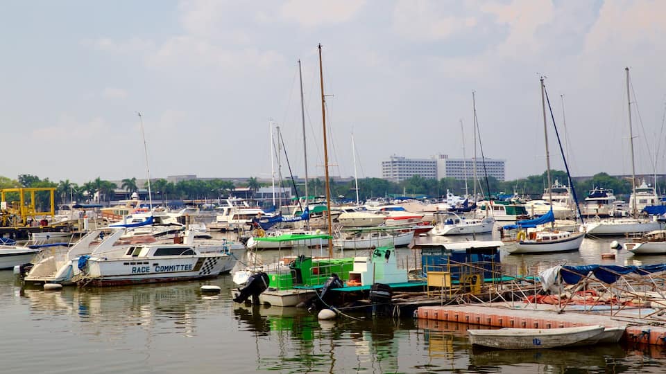 A marina with numerous boats docked, a crane, and a distant building.