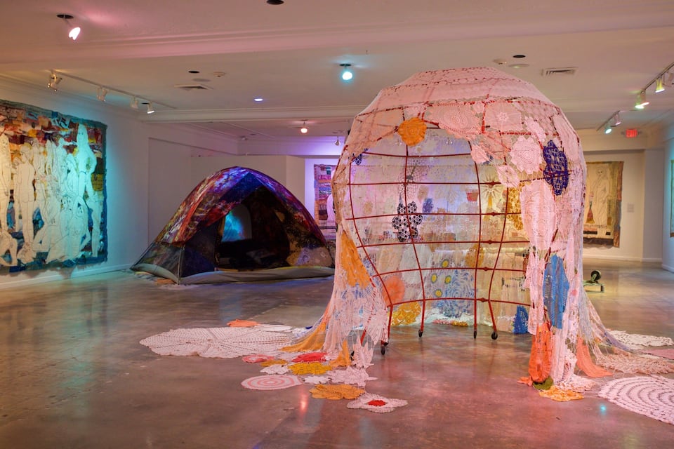 An art gallery with large, colorful installations and a textured wall.