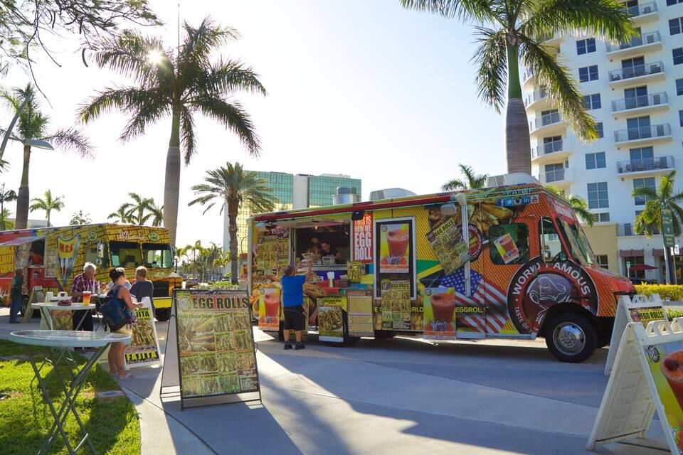 Um food truck colorido com temática tropical estacionado em uma calçada.