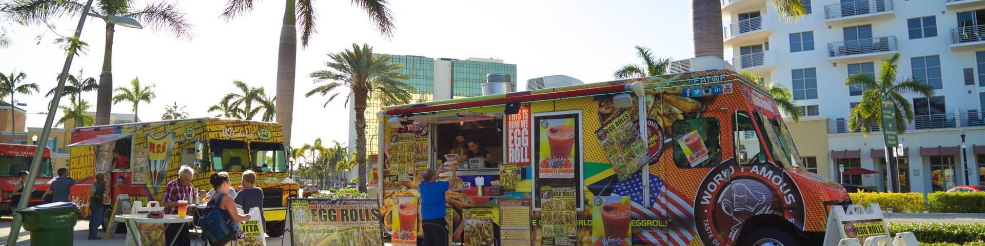 Um food truck colorido com temática tropical estacionado em uma calçada.