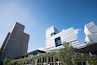 Eine moderne Skyline mit hohen Gebäuden, darunter ein markanter Glaskrach und ein Gebäude mit einem besonderen geometrischen Design.