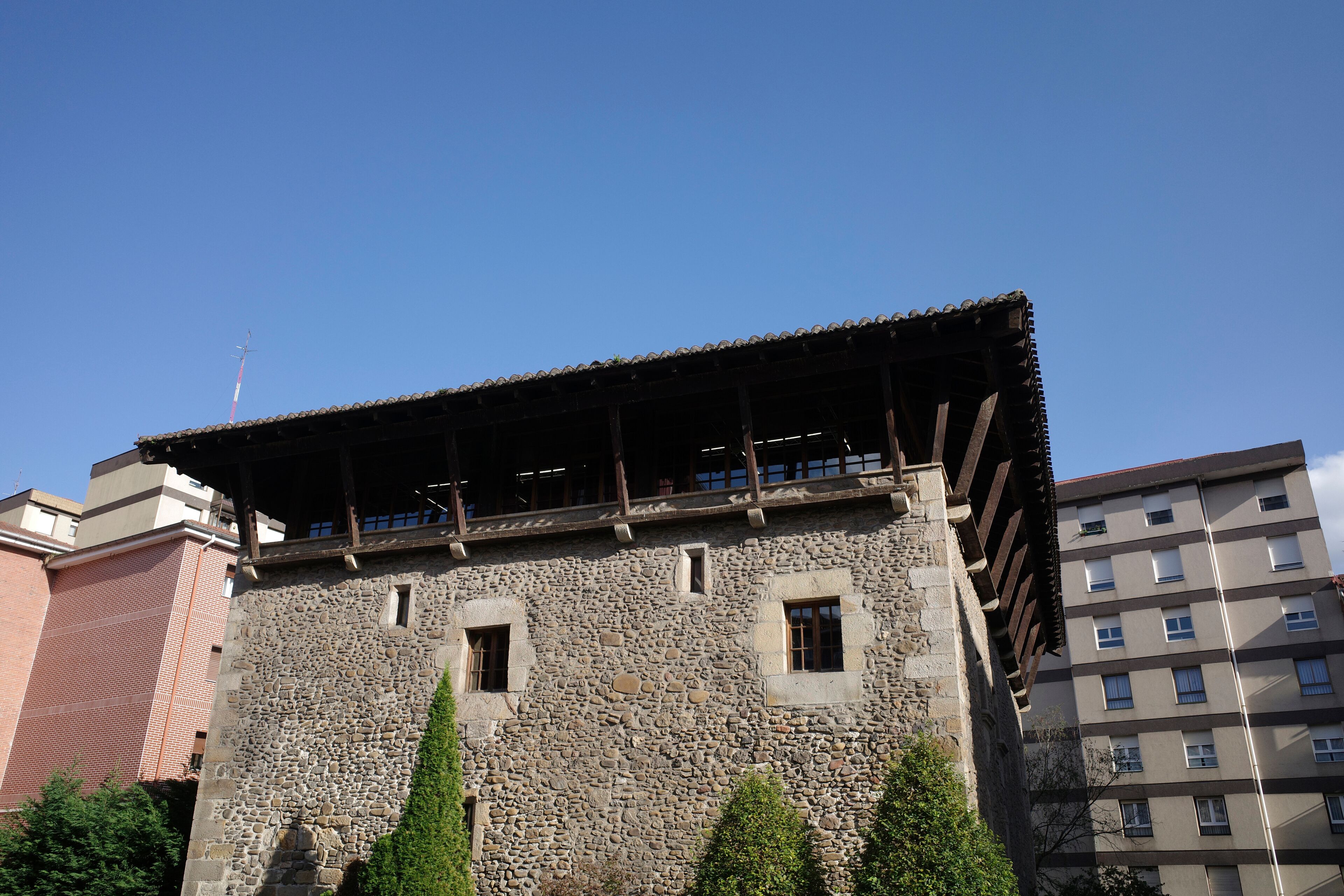 A stone building with a tiled roof and several windows.