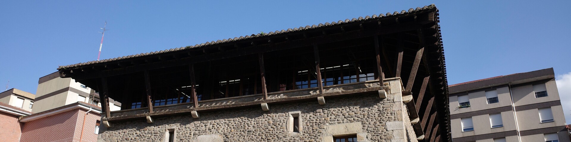 A stone building with a tiled roof and several windows.