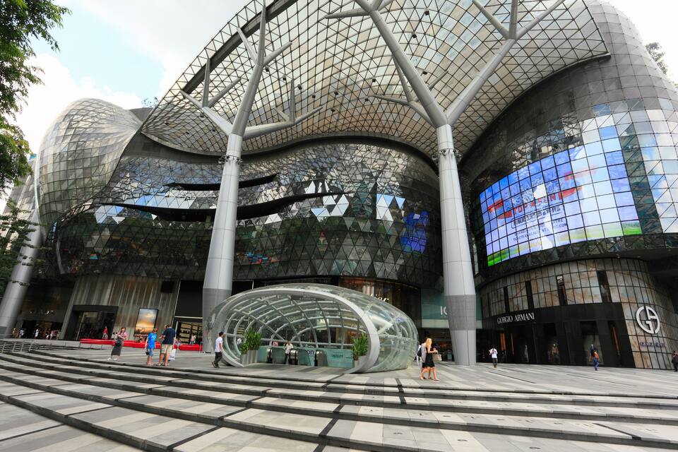Un bâtiment d’architecture moderne doté d’une façade en verre incurvée et d’un grand écran numérique.