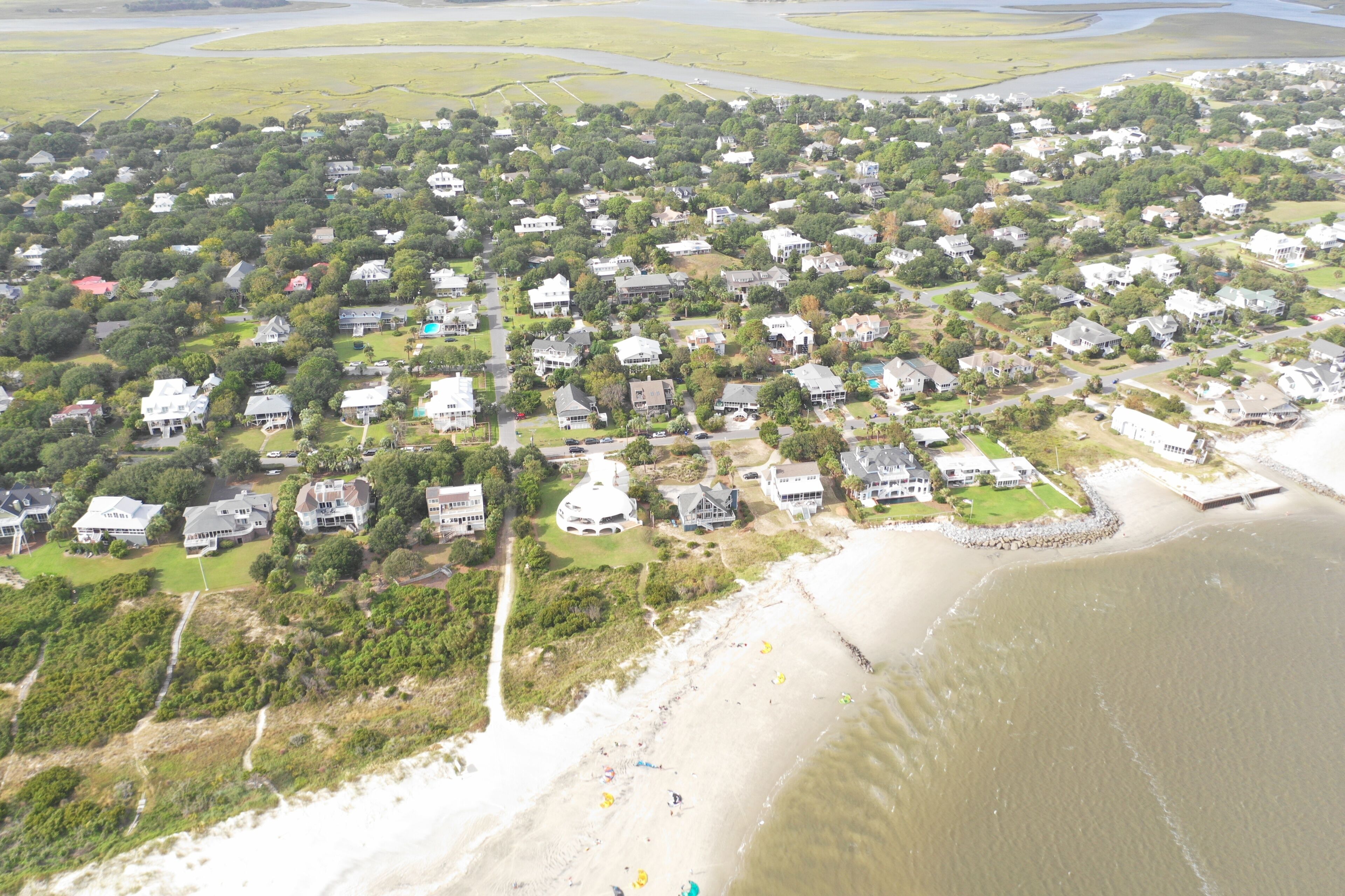 Vista aérea de uma área residencial costeira com casas, praia e rio.
