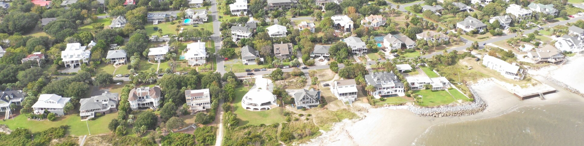 Vista aérea de uma área residencial costeira com casas, praia e rio.