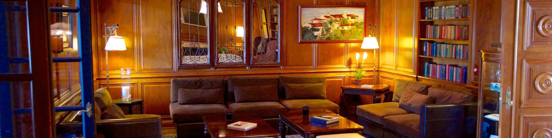 A cozy living room with wooden paneling, a chandelier, a bookshelf, and a painting on the wall.